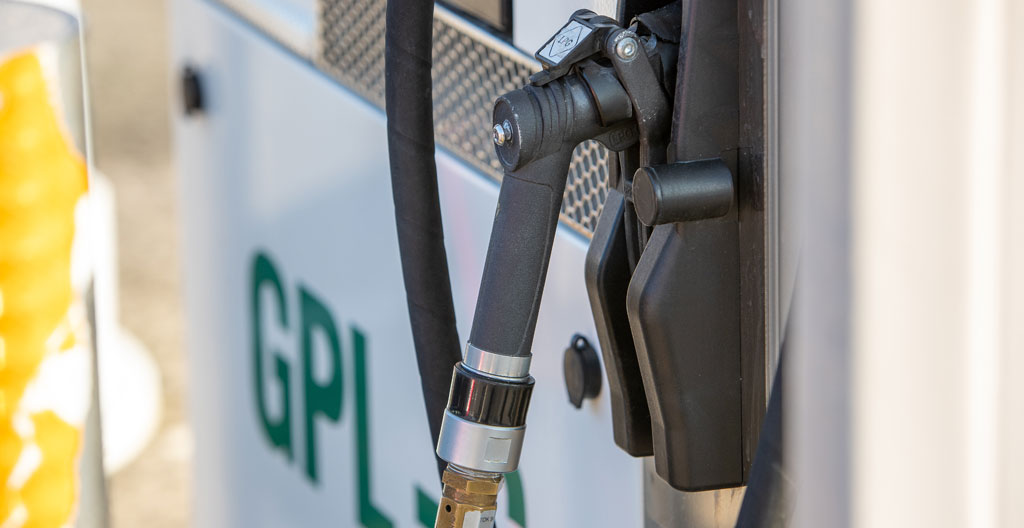 Vue rapprochée d'un pistolet de distribution GPL chromé avec détails de la buse métallique, arrière-plan flouté créant un effet bokeh sur les équipements de la station